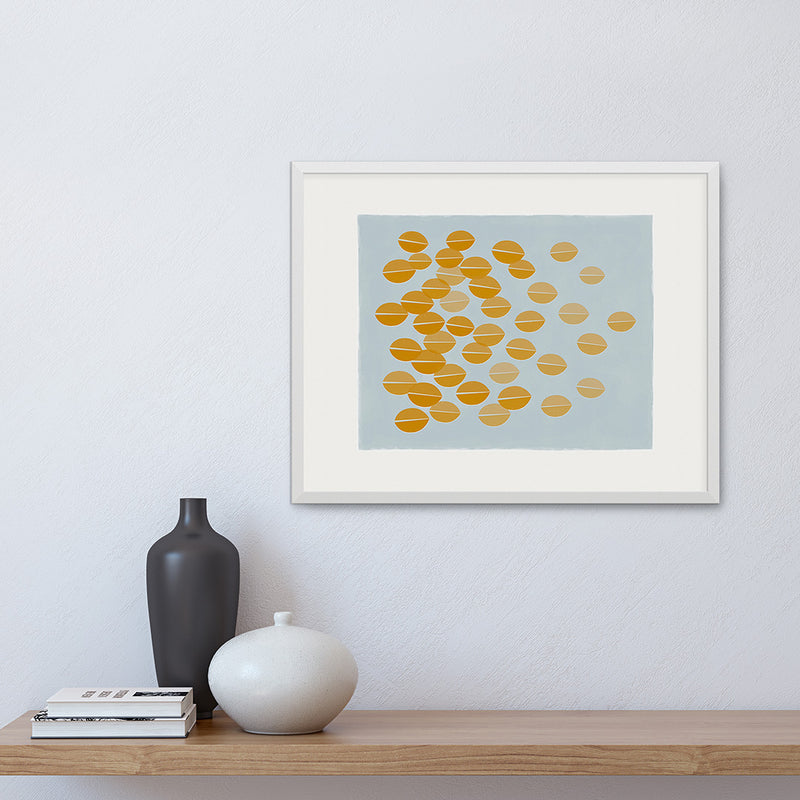 White framed version of a graphic print of ochre leaves rustling in the breeze by Janet Taylor | Household Art.